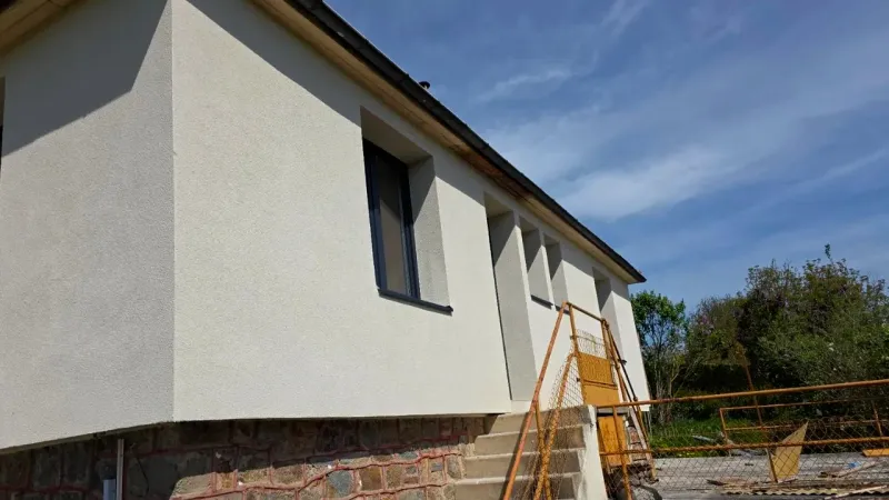 Maison isolée par l'extérieur : façade neuve sous enduit, encadrements de fenêtres refaits